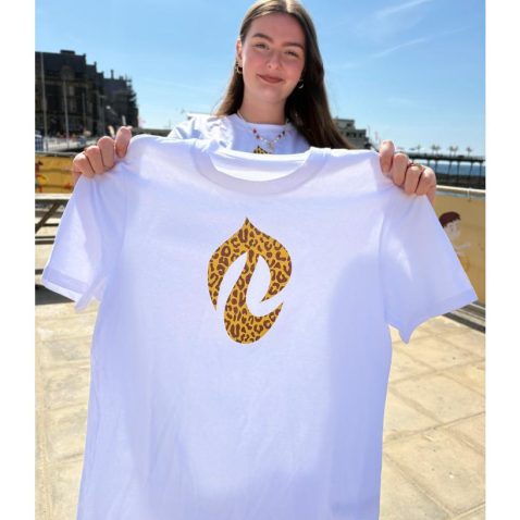 Llun merch yn dal crys-T gwyn gyda tafod print llewpart